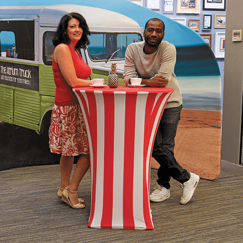 a man and woman standing beside a fabric table drinking coffee